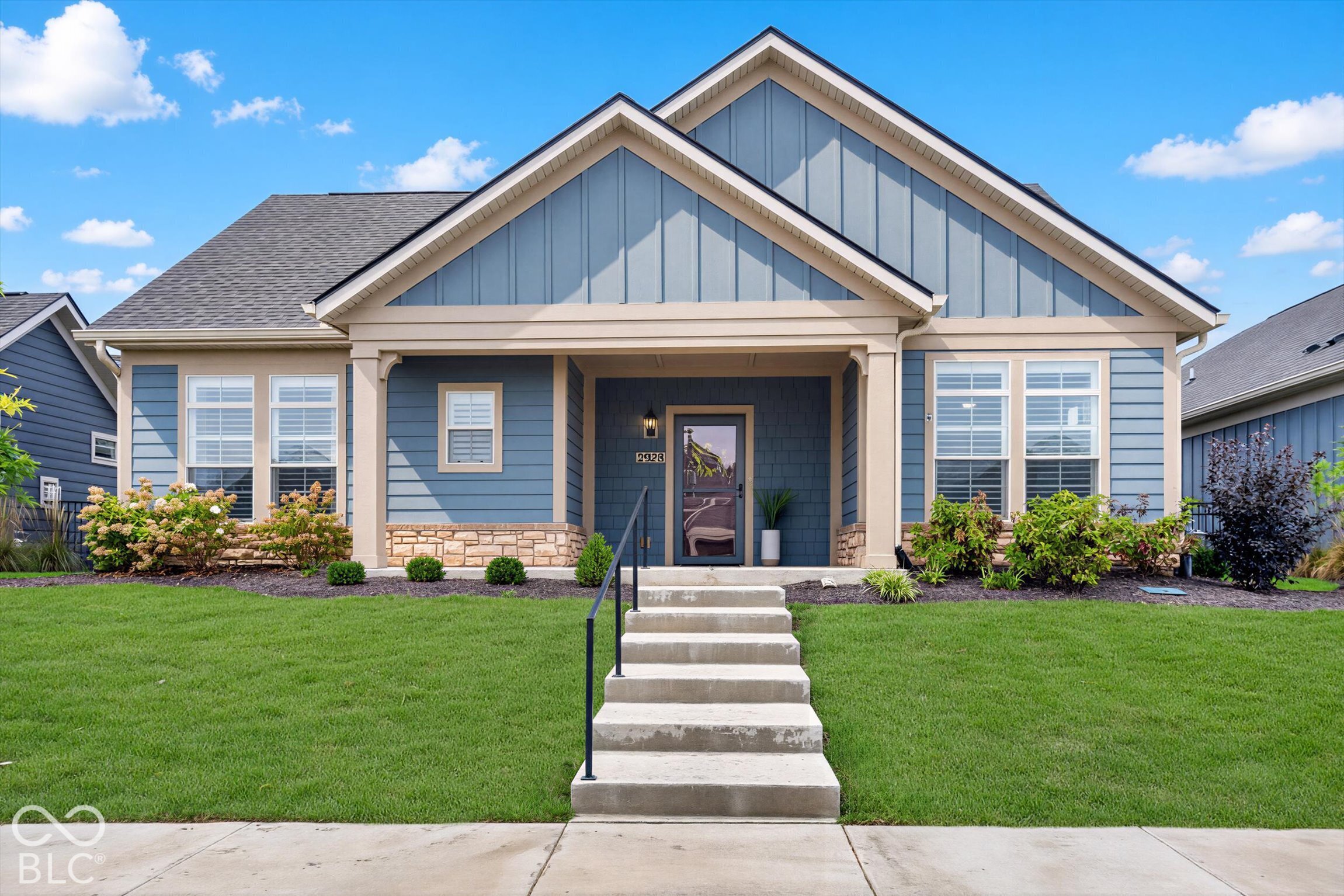 Blue-sided house with steep gables, stone accents, and front steps leading to a covered entry.