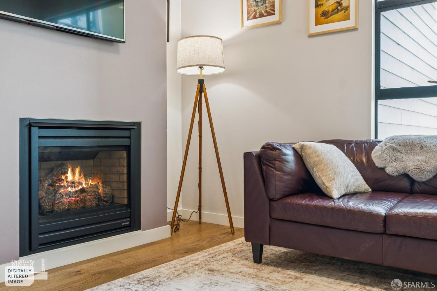 Living room with a lit fireplace, leather sofa, and tripod floor lamp.