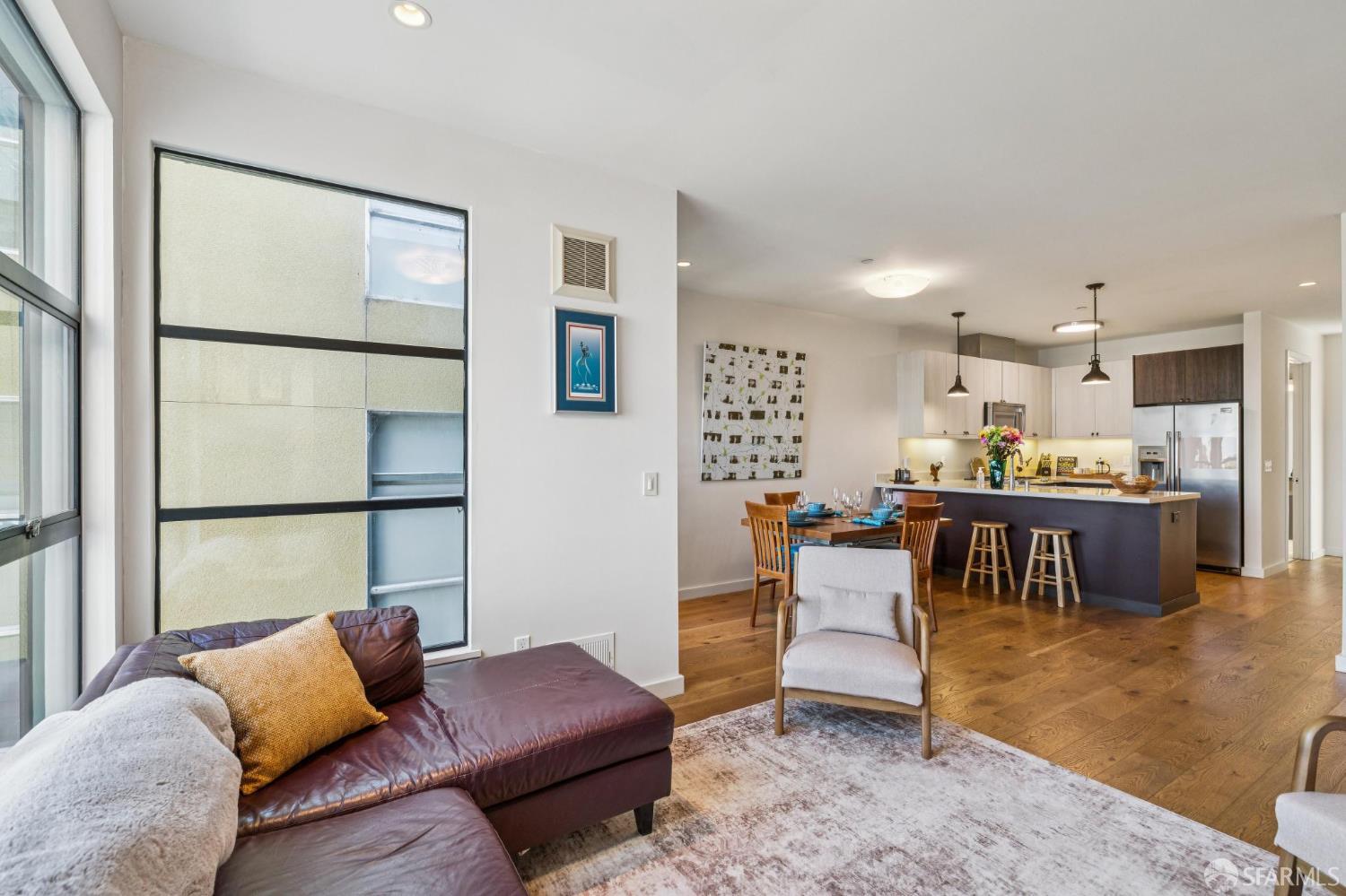 Open-plan living room with a leather sectional, dining area, and kitchen island.