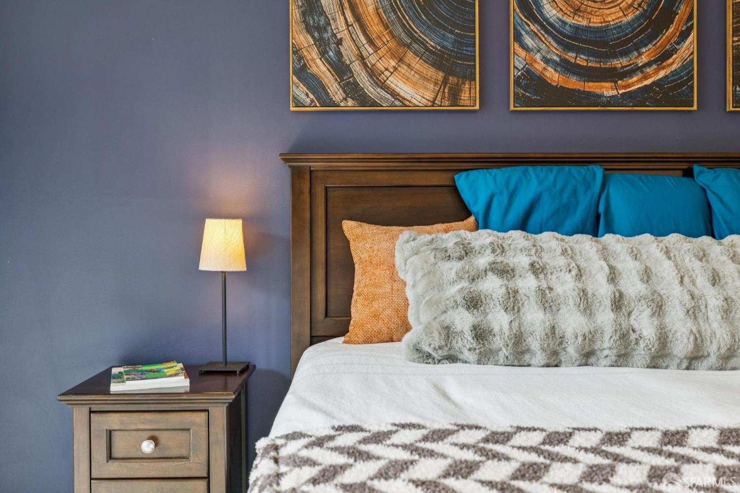 Bedroom with a dark wood bed, turquoise pillows, gray faux-fur throw, and blue-gray walls.