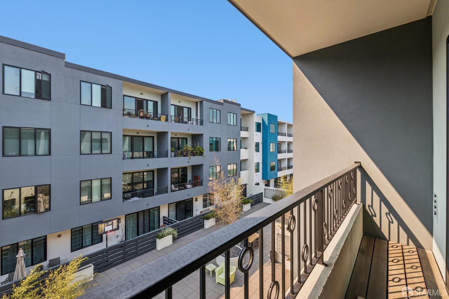 Condominium balcony overlooking a shared courtyard and neighboring modern apartment buildings.