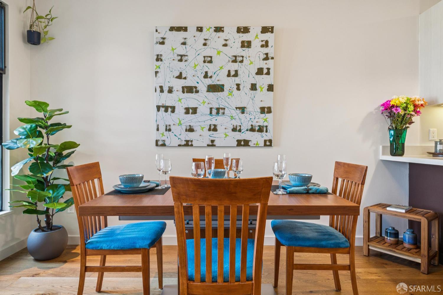 Staged dining room with a wooden table set for dining, blue chair cushions, and hardwood floors.