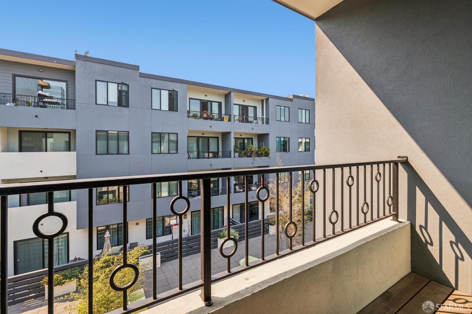 Condominium balcony overlooking a landscaped courtyard and modern apartment building.