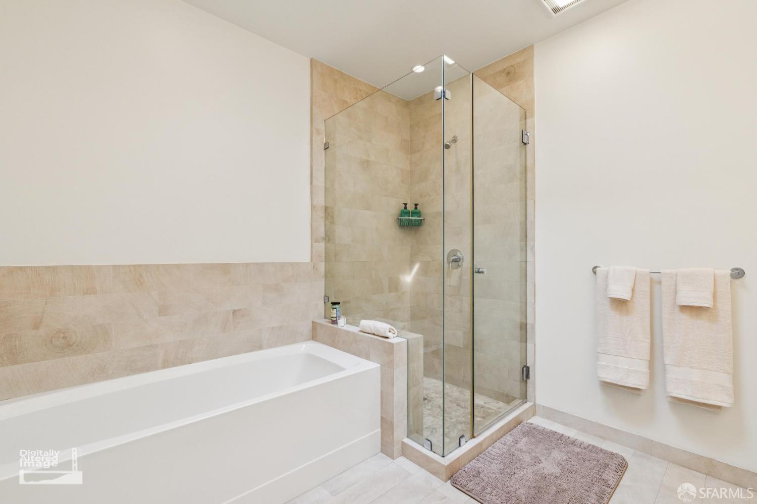 Bathroom with a white bathtub and glass shower, finished in beige stone tile.