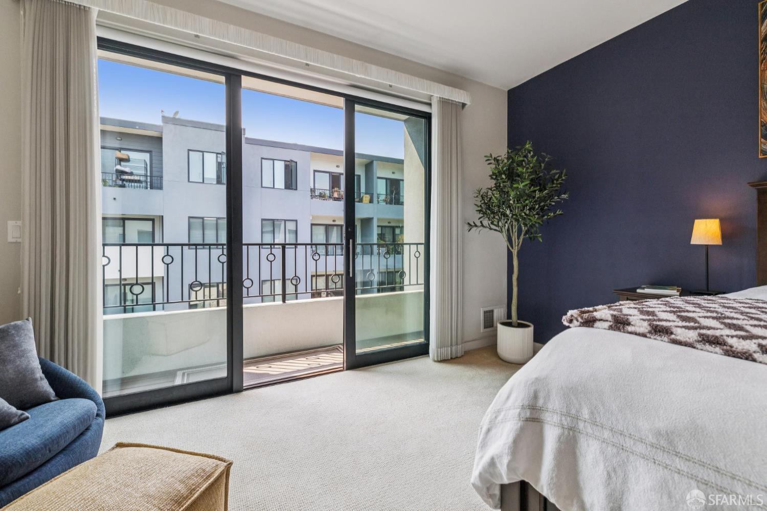Staged bedroom with a navy accent wall and sliding glass doors opening onto a balcony.