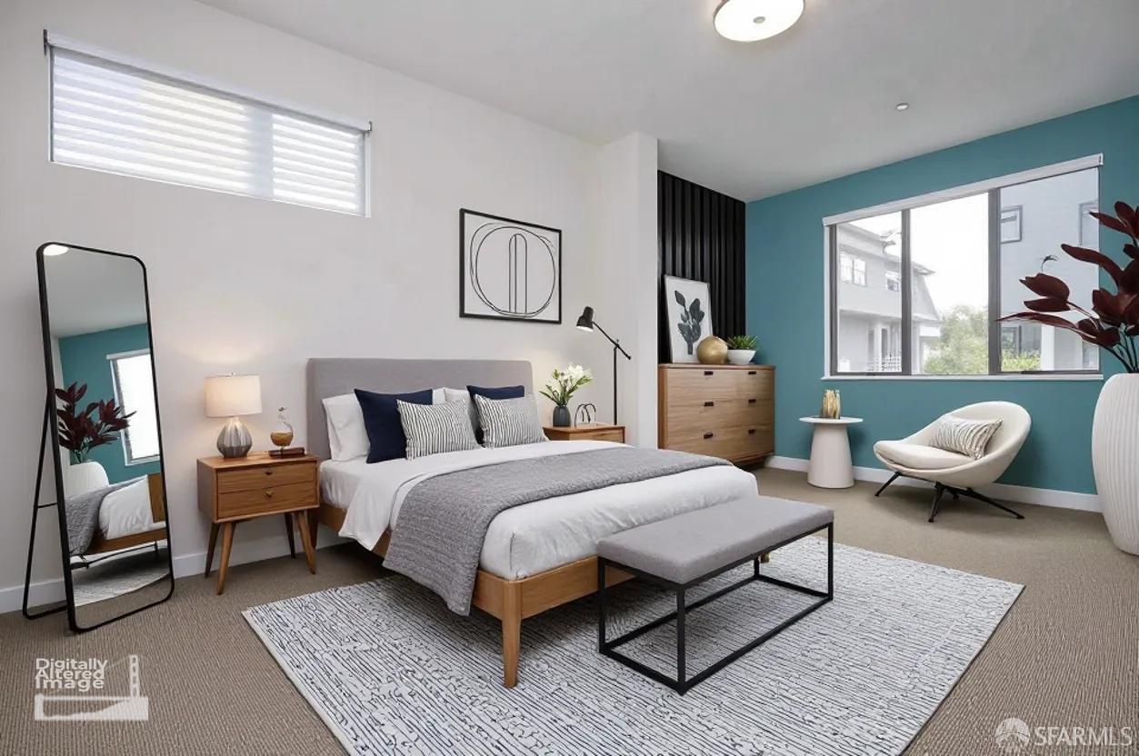 Staged bedroom with a wood-frame bed, patterned rug, teal accent wall, and large window.