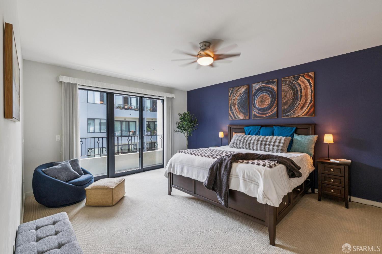 Bedroom with a deep blue accent wall, circular artwork, and sliding glass doors to a balcony.