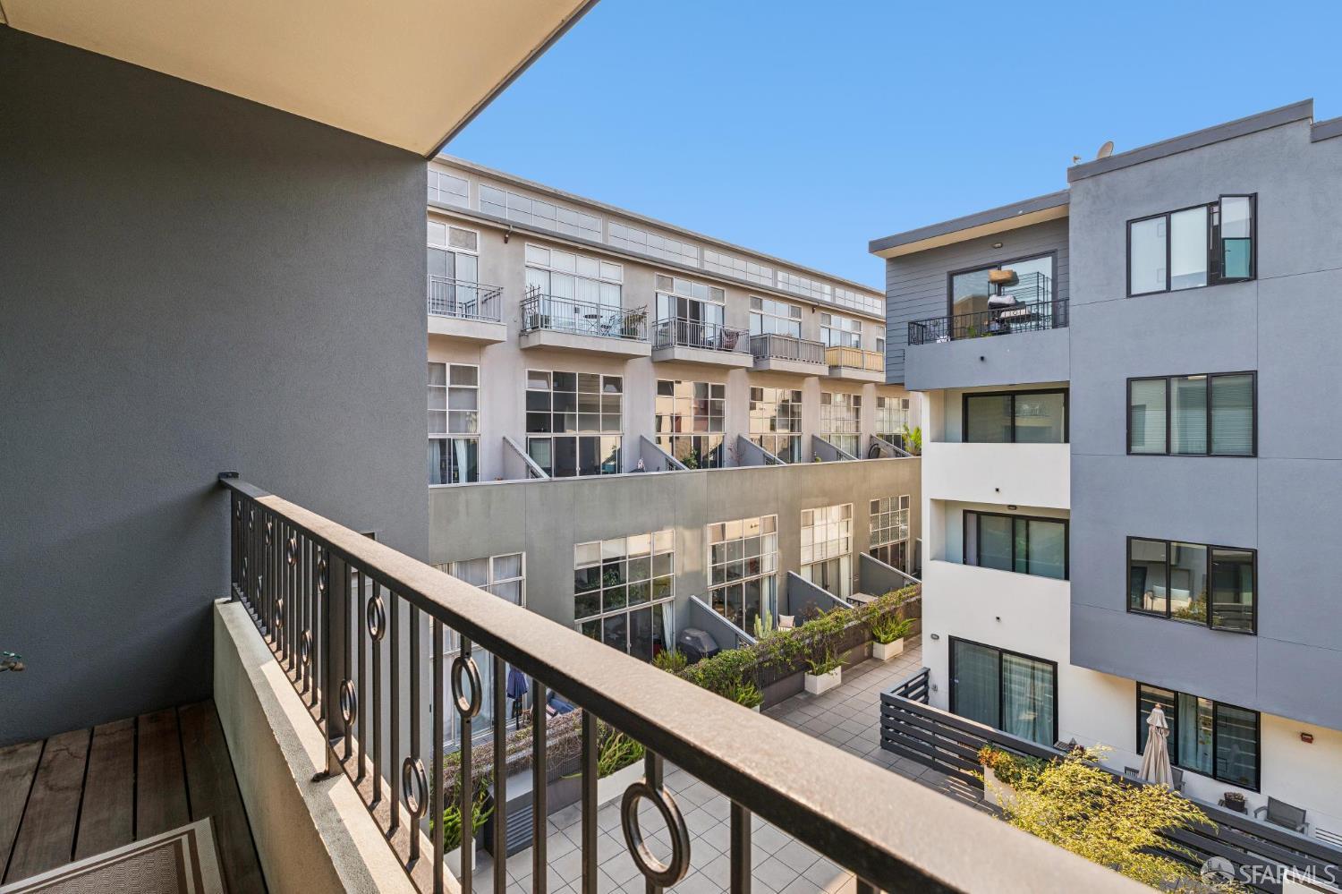Condominium balcony overlooking a landscaped courtyard and surrounding modern residences.