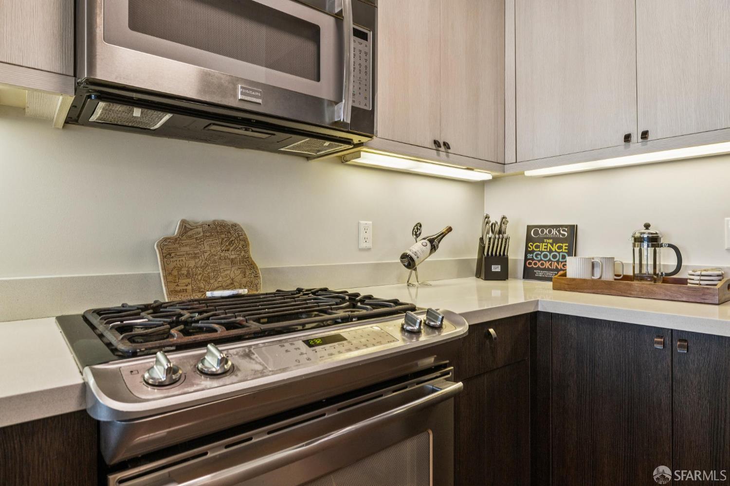 Kitchen with a stainless steel gas range, pale countertops, and contrasting light and dark cabinets.