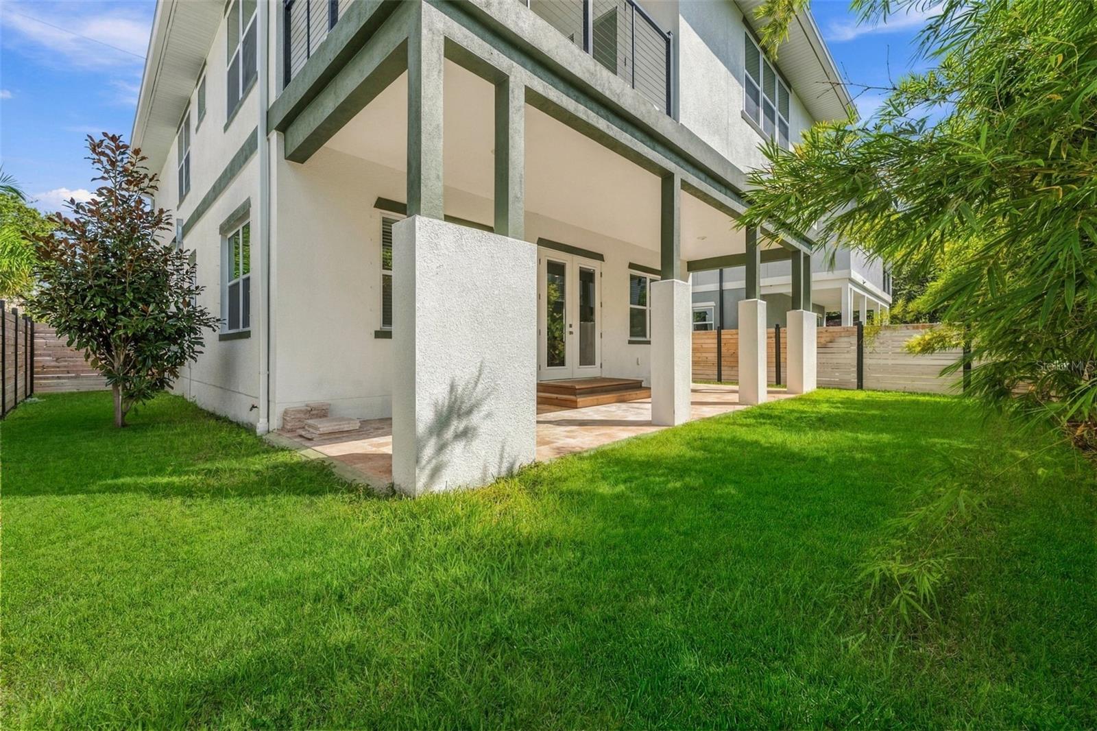 Two-story stucco home with a covered patio and spacious green backyard.