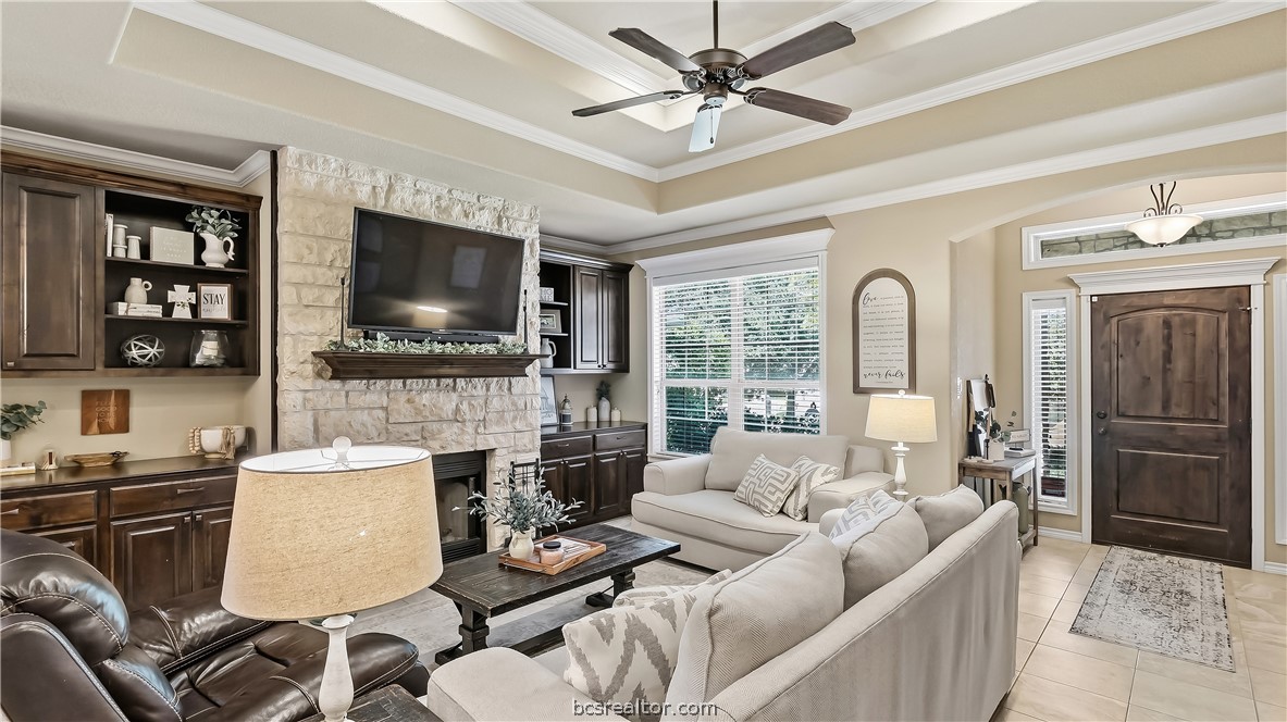 Living room with stone fireplace, built-in dark wood cabinetry, and neutral sofas.