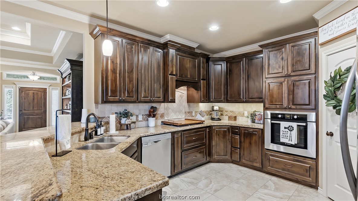 Kitchen with dark wood cabinets, granite counters, and stainless steel appliances.