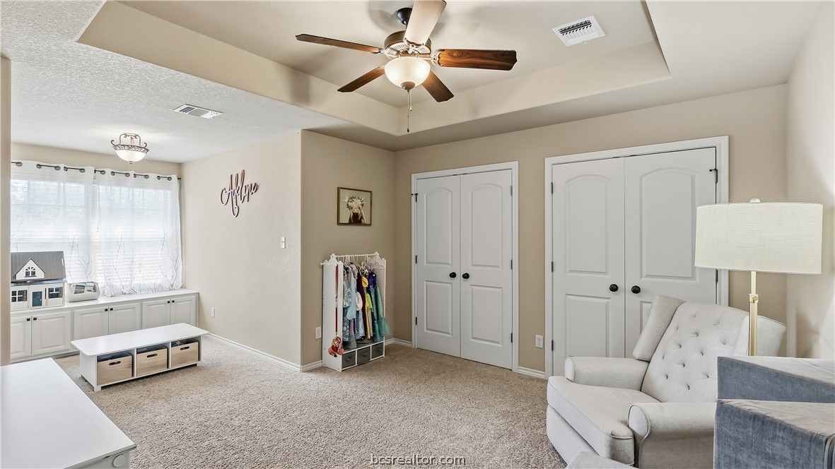 Playroom with built-in window cabinets, toy storage, and a ceiling fan.