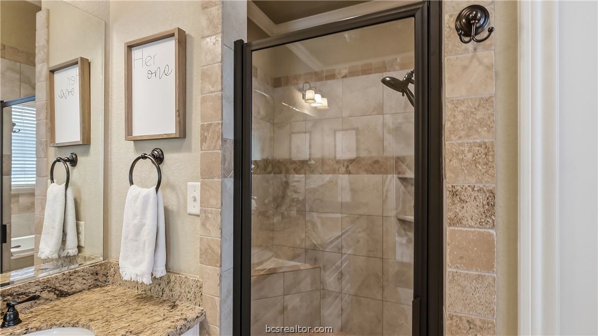 Bathroom with a glass-enclosed tiled shower and granite vanity.