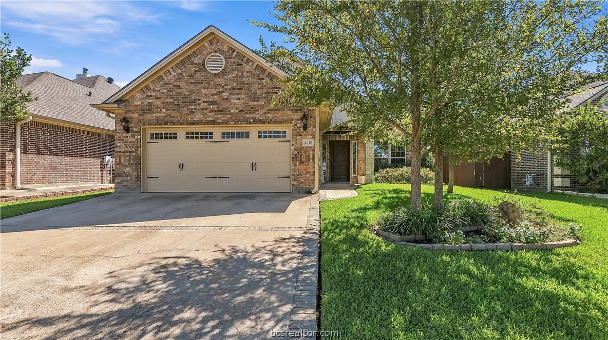 Brick home with a two-car garage, shaded front entry, and landscaped lawn.