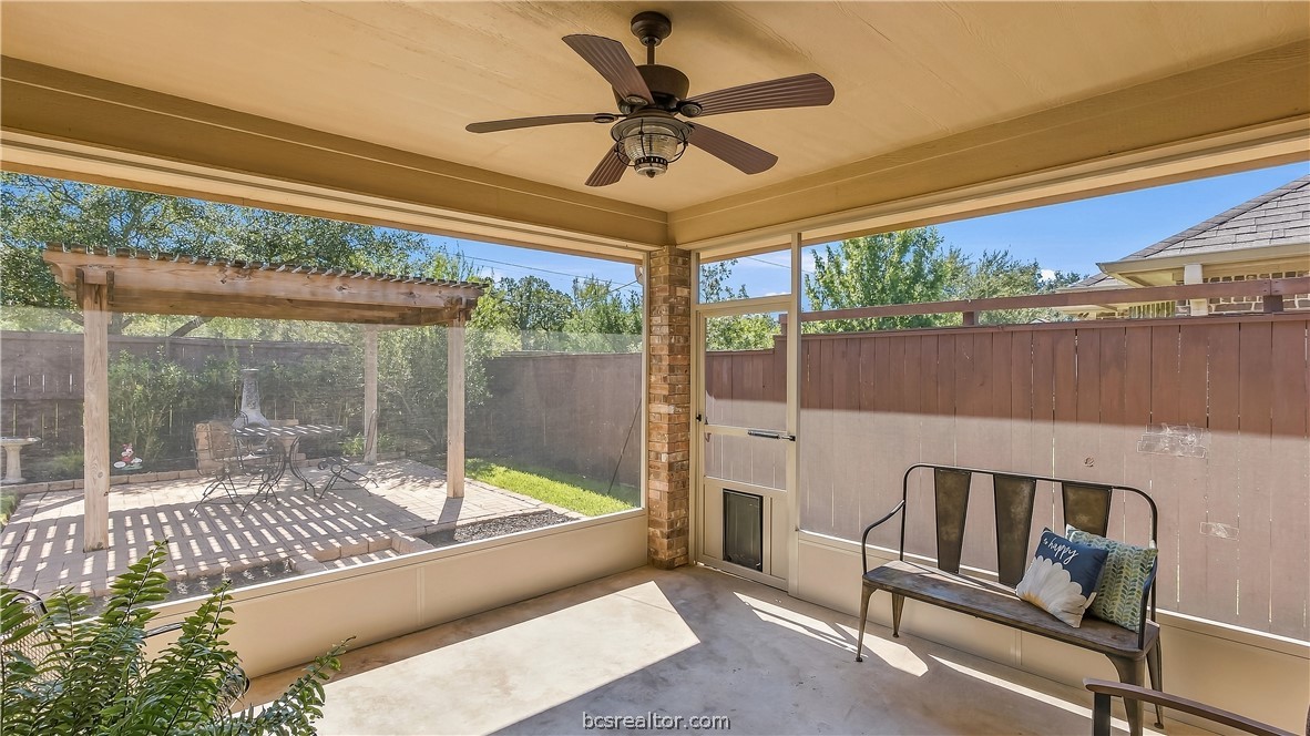 Screened porch with ceiling fan, bench seating, and views of a fenced backyard patio.