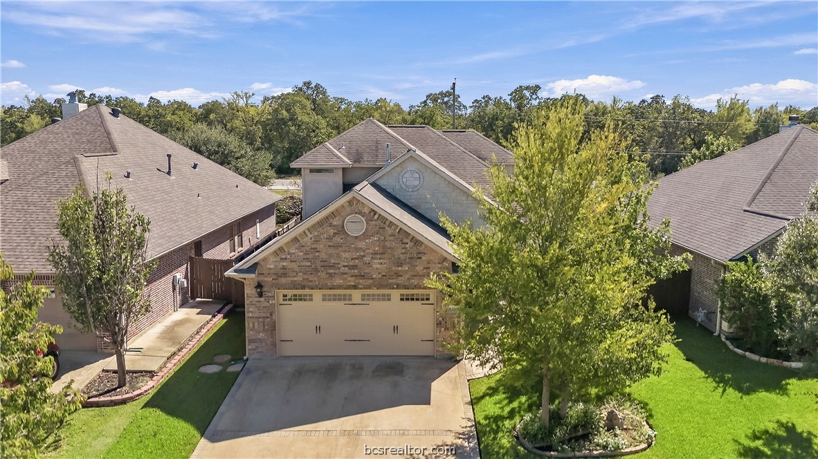 Brick-front home with a double garage, driveway, and landscaped front yard.