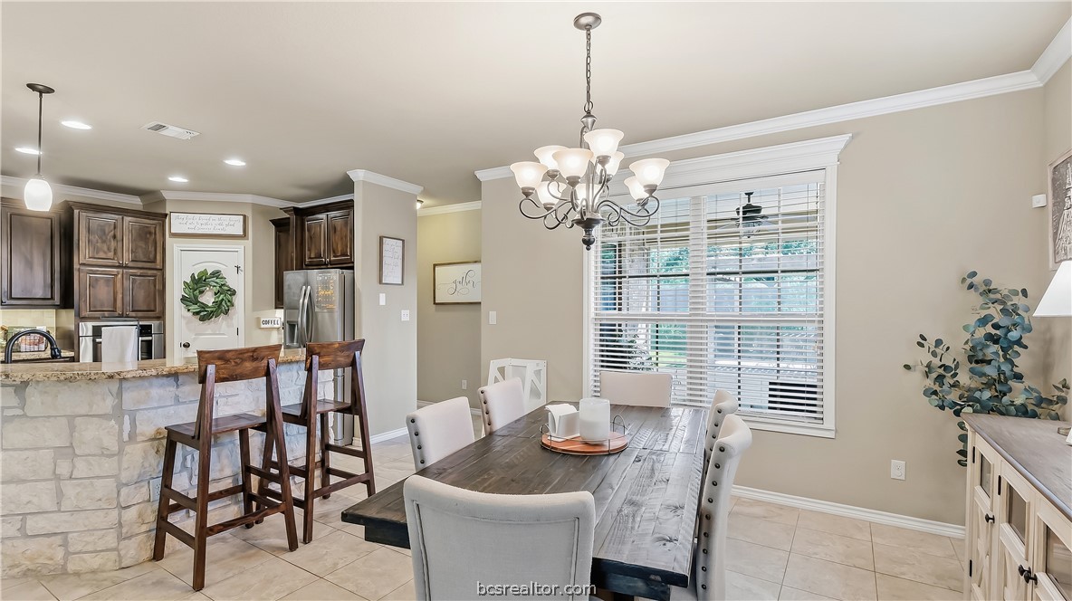 Dining room with a dark wood table beside an open kitchen and stone breakfast bar.