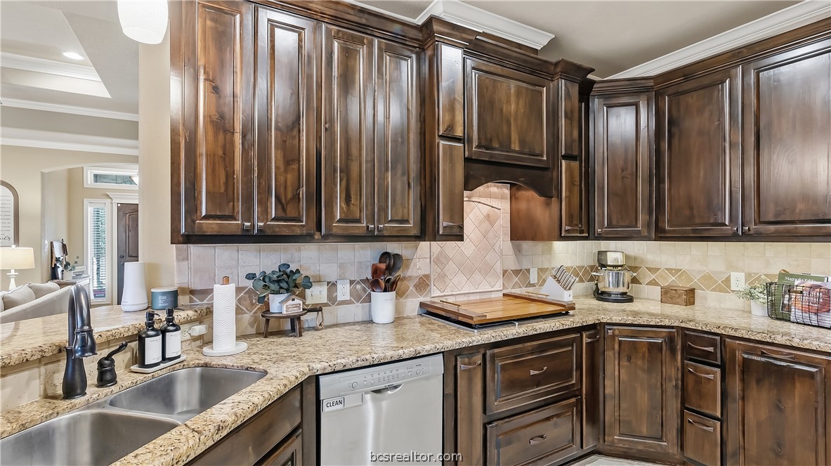 Kitchen with dark wood cabinets, granite counters, and a stainless steel dishwasher.