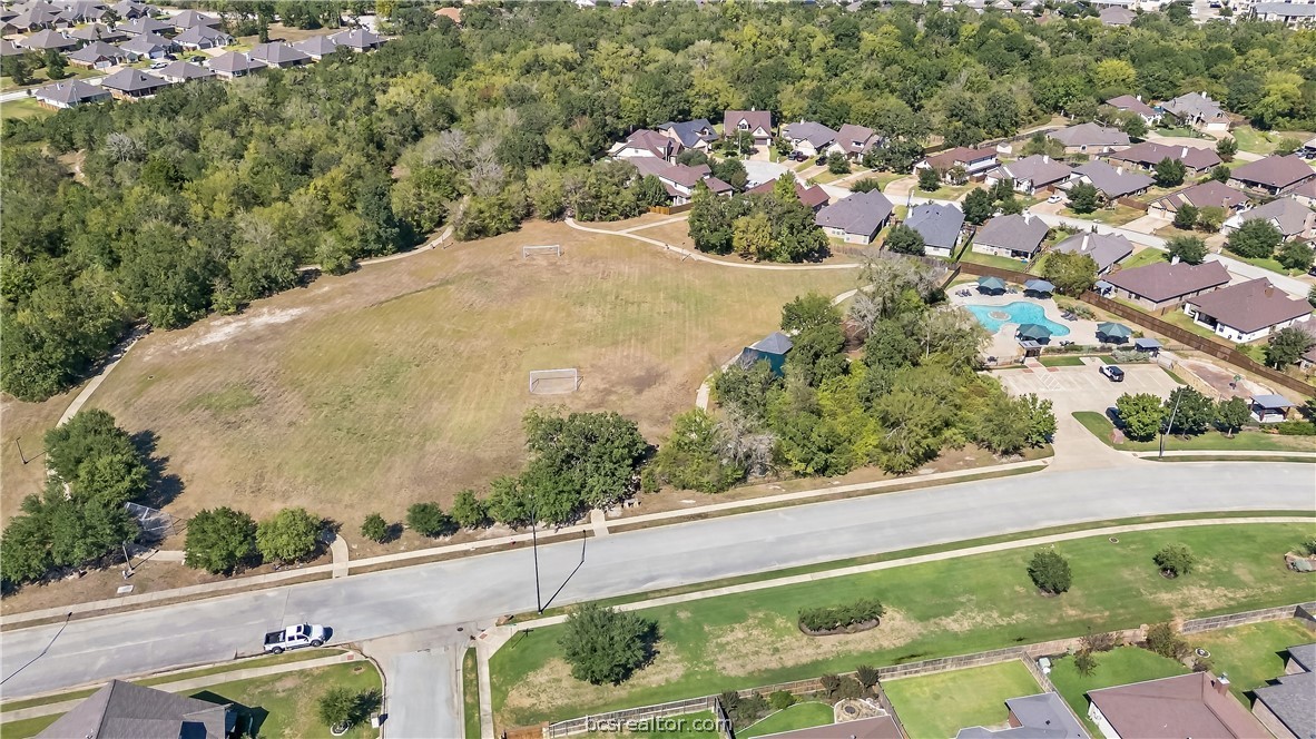 Aerial view of a neighborhood green space with soccer goals and a nearby community pool.