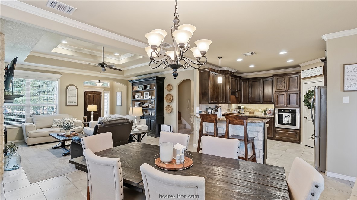 Open living, dining, and kitchen area with dark wood cabinetry and a stone island.