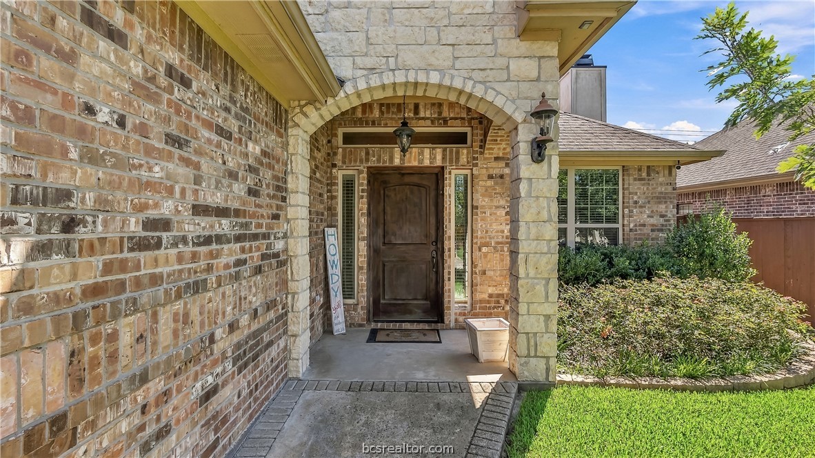 Brick-and-stone home entrance with an arched porch and dark wood front door.