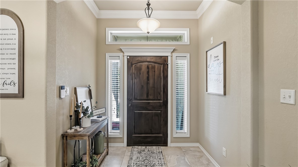 Entry foyer with a dark wood front door, narrow sidelights, and a tiled floor.