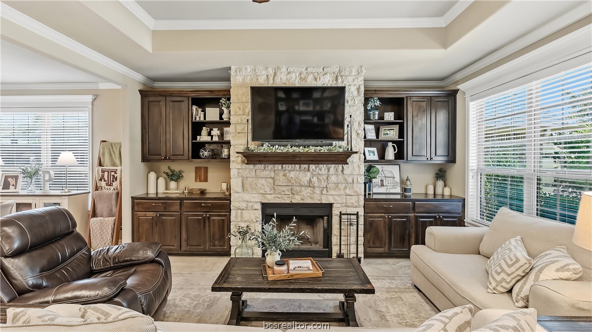 Living room with a stone fireplace, built-in dark wood cabinetry, and seating around a coffee table.