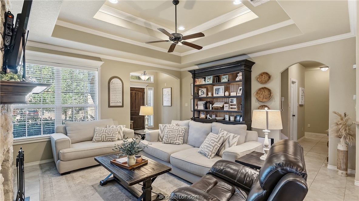 Living room with a coffered ceiling, pale sectional sofas, and dark built-in shelving.