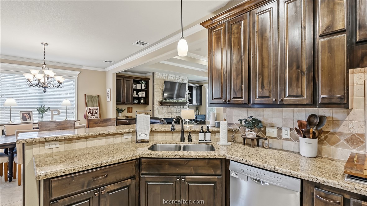 Kitchen with dark wood cabinets, granite counters, and a double sink opening to the dining area.