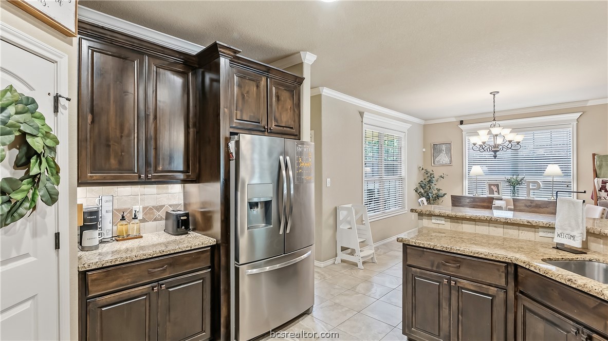 Kitchen with dark wood cabinets, stainless steel refrigerator, granite counters, and a breakfast nook.