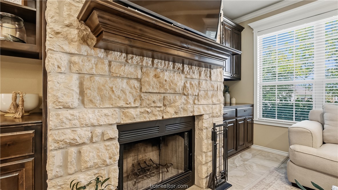 Living room with a limestone fireplace, dark built-in cabinetry, and a large window.