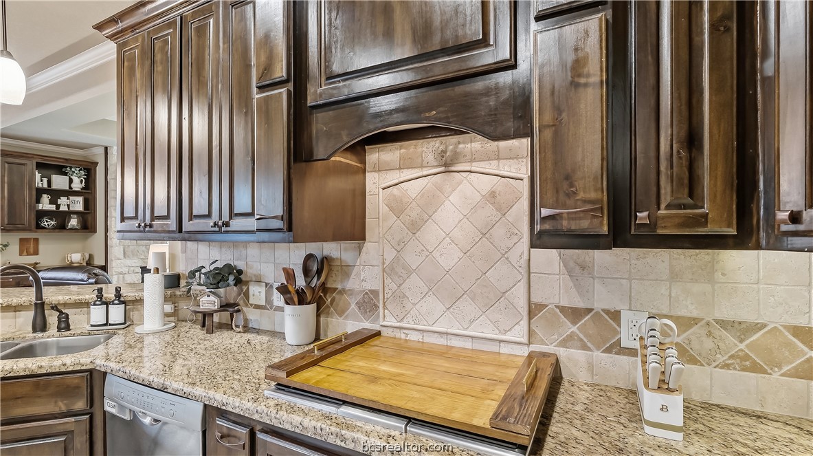 Kitchen with dark wood cabinets, a decorative tile backsplash, and granite countertops.