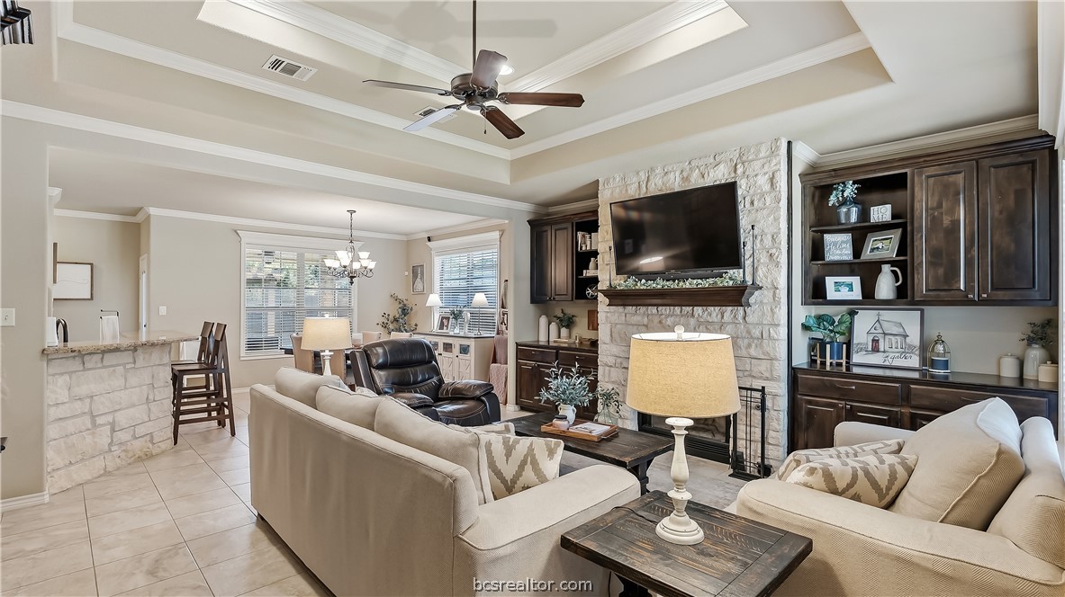 Living room with a stone fireplace, built-in cabinetry, and an open dining area.
