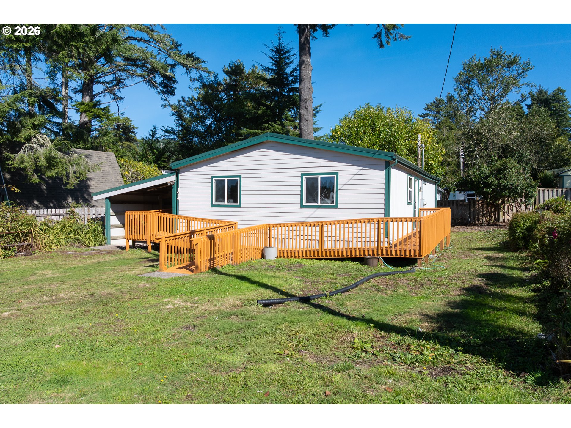 Single-story home with teal trim and a long orange accessibility ramp and deck.