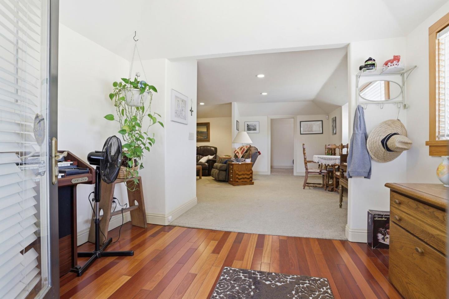 Furnished living area with hardwood entry flooring, carpeted lounge, and adjoining dining nook.