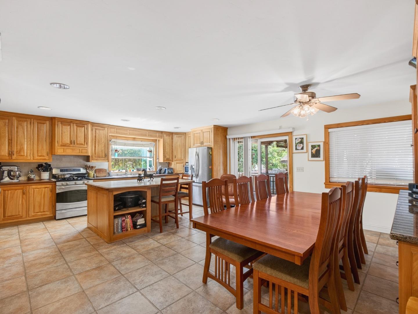 Kitchen and dining area with wood cabinetry, a central island, and a large dining table.