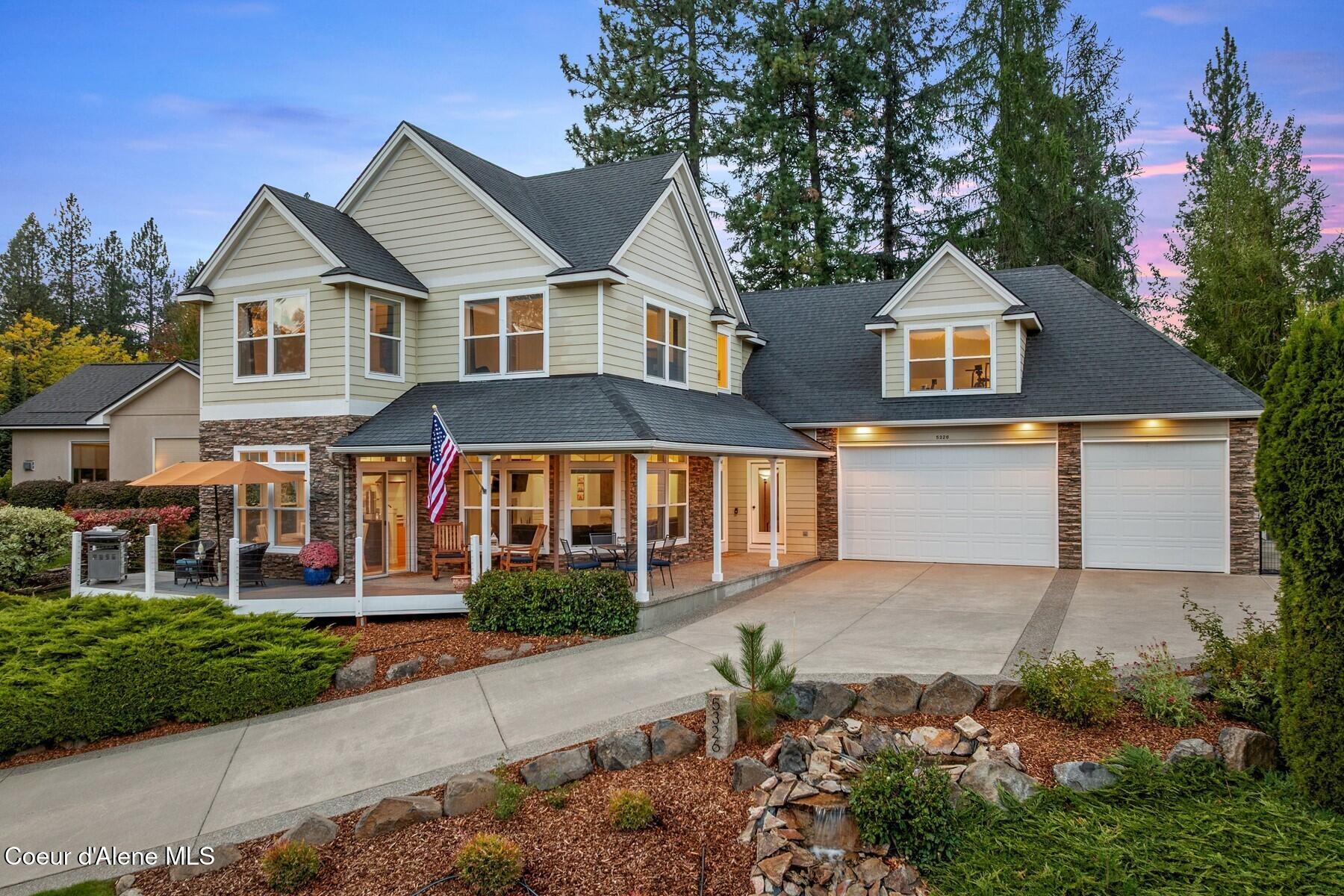 Two-story home with stone accents, a covered patio, and double garage at dusk.