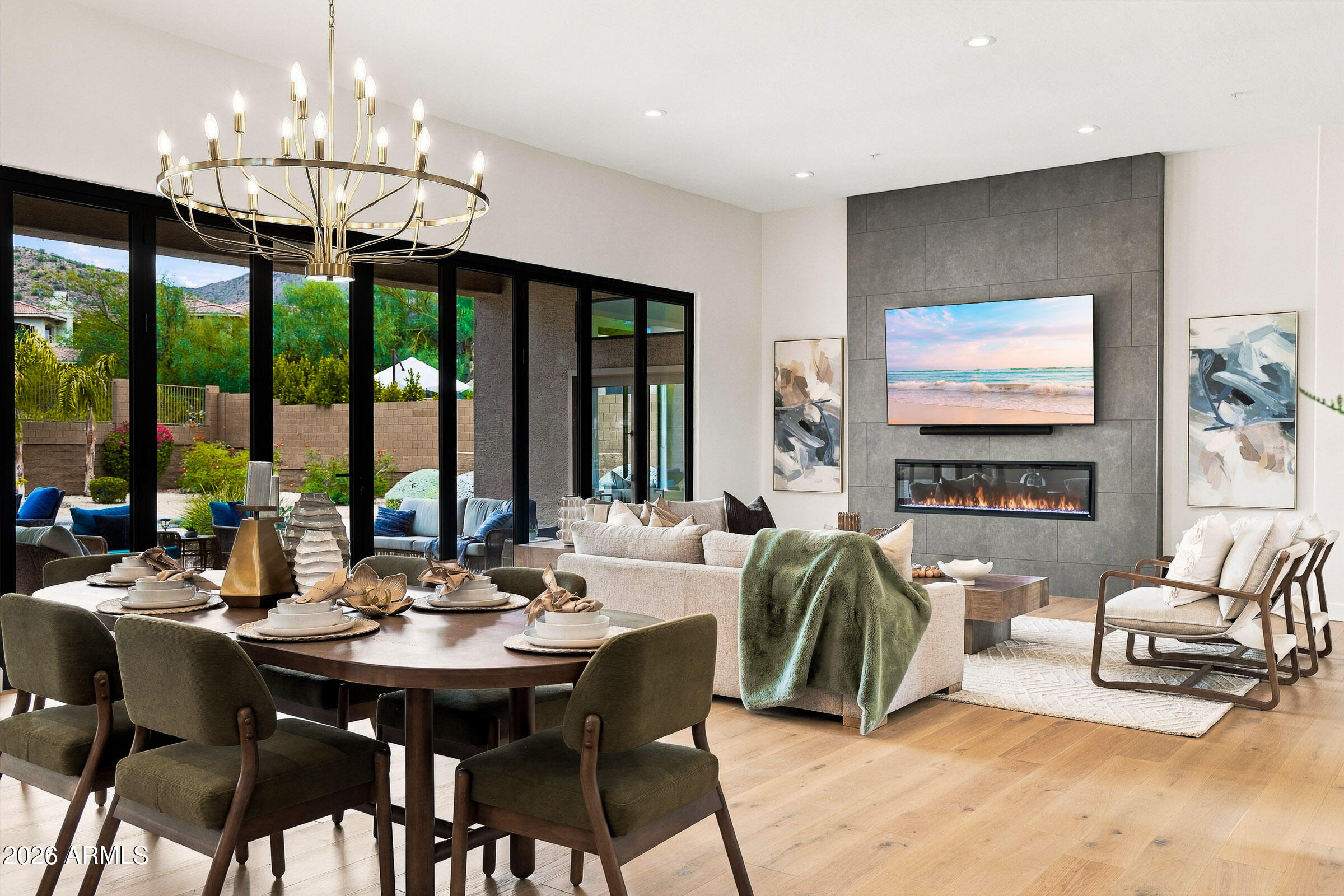 Open-plan living and dining room with a tiled fireplace wall, chandelier, and sliding glass doors to the patio.