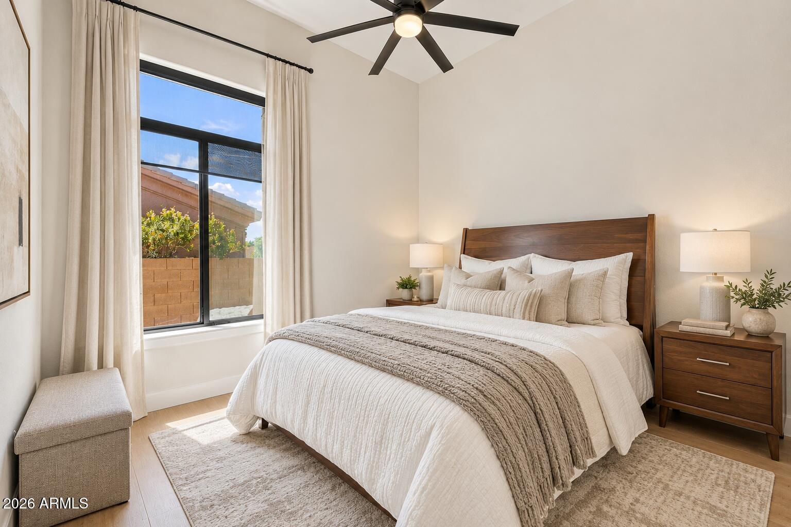Bedroom with a large white bed, dark wood headboard, and tall curtained window.