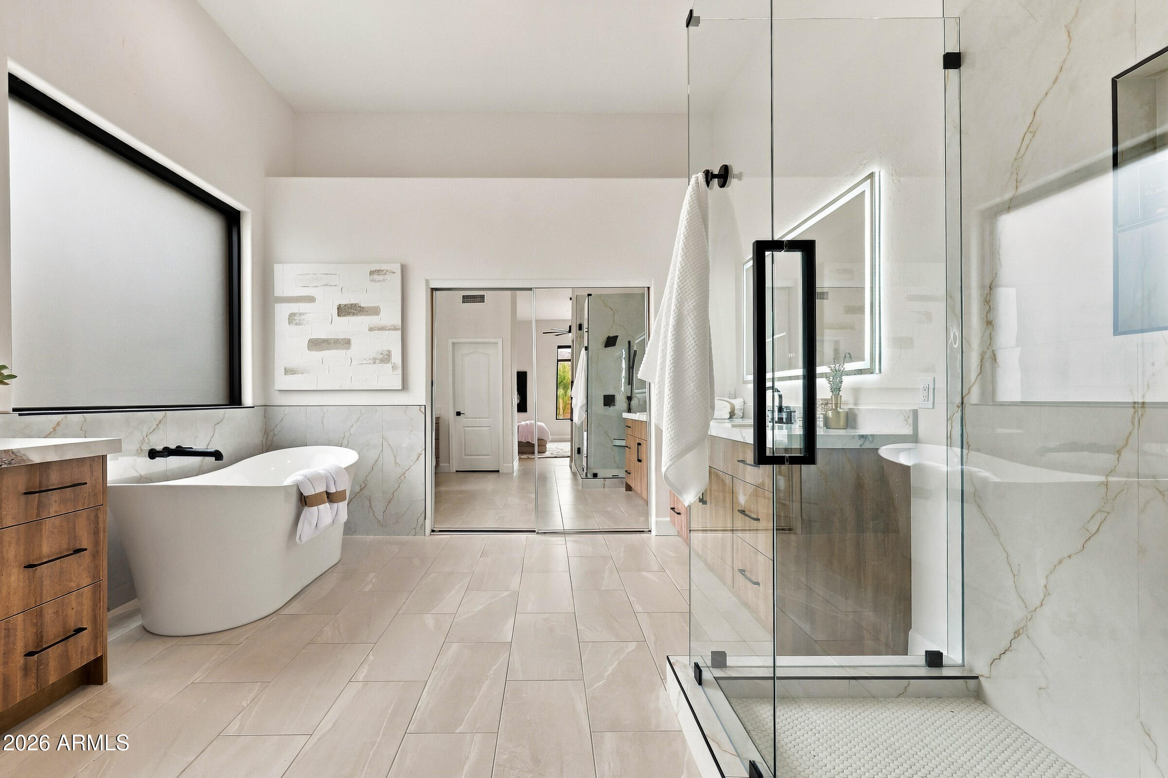 Modern bathroom with a freestanding tub, glass shower, and pale veined tile.