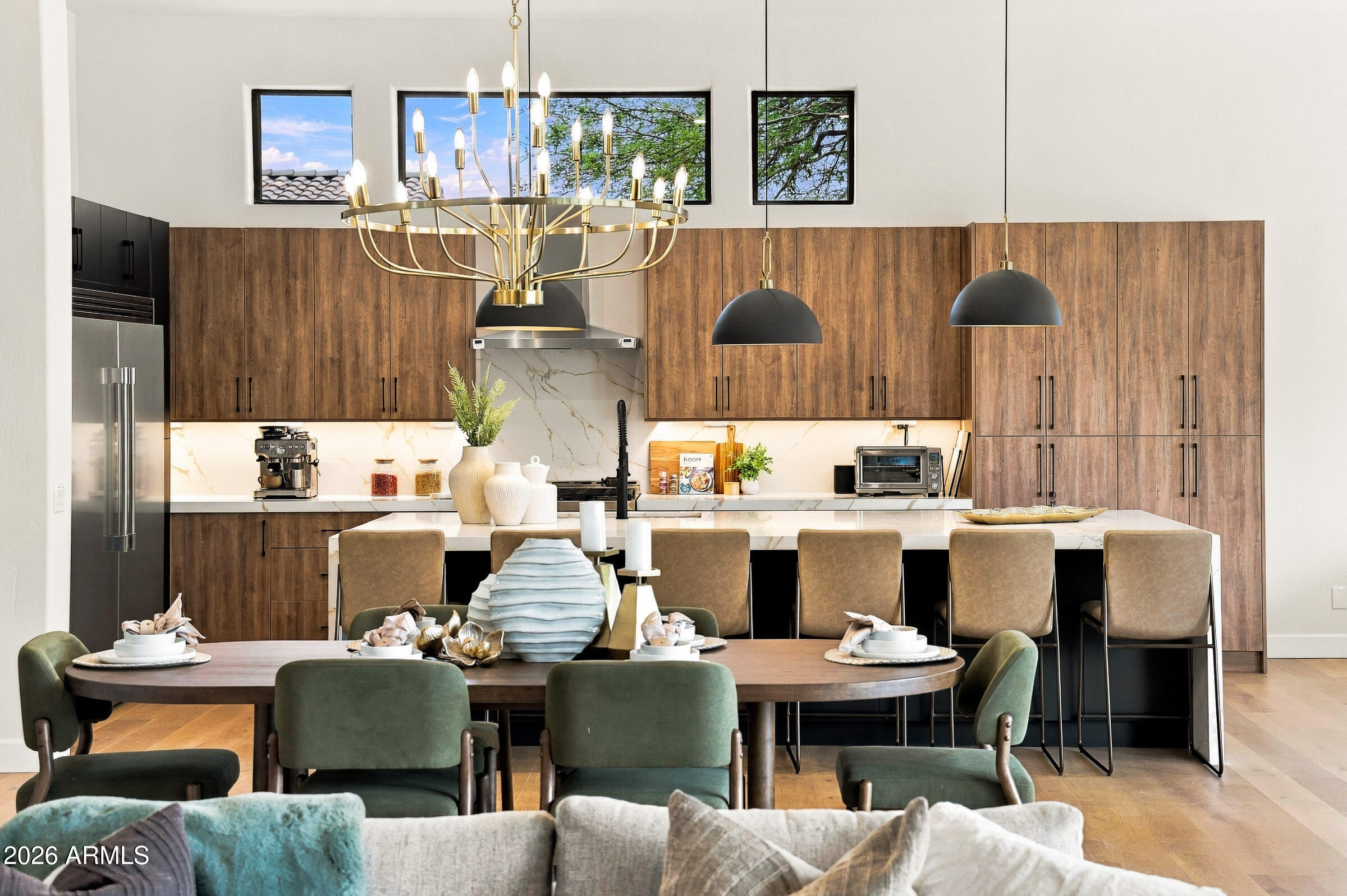Modern kitchen with wood cabinetry, a marble-look island, bar seating, and an adjacent dining area.