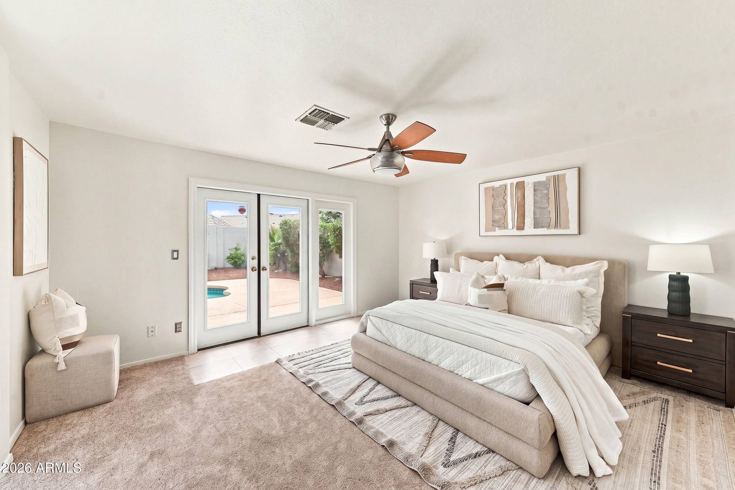 Staged bedroom with a large upholstered bed and glass doors overlooking a patio and pool.