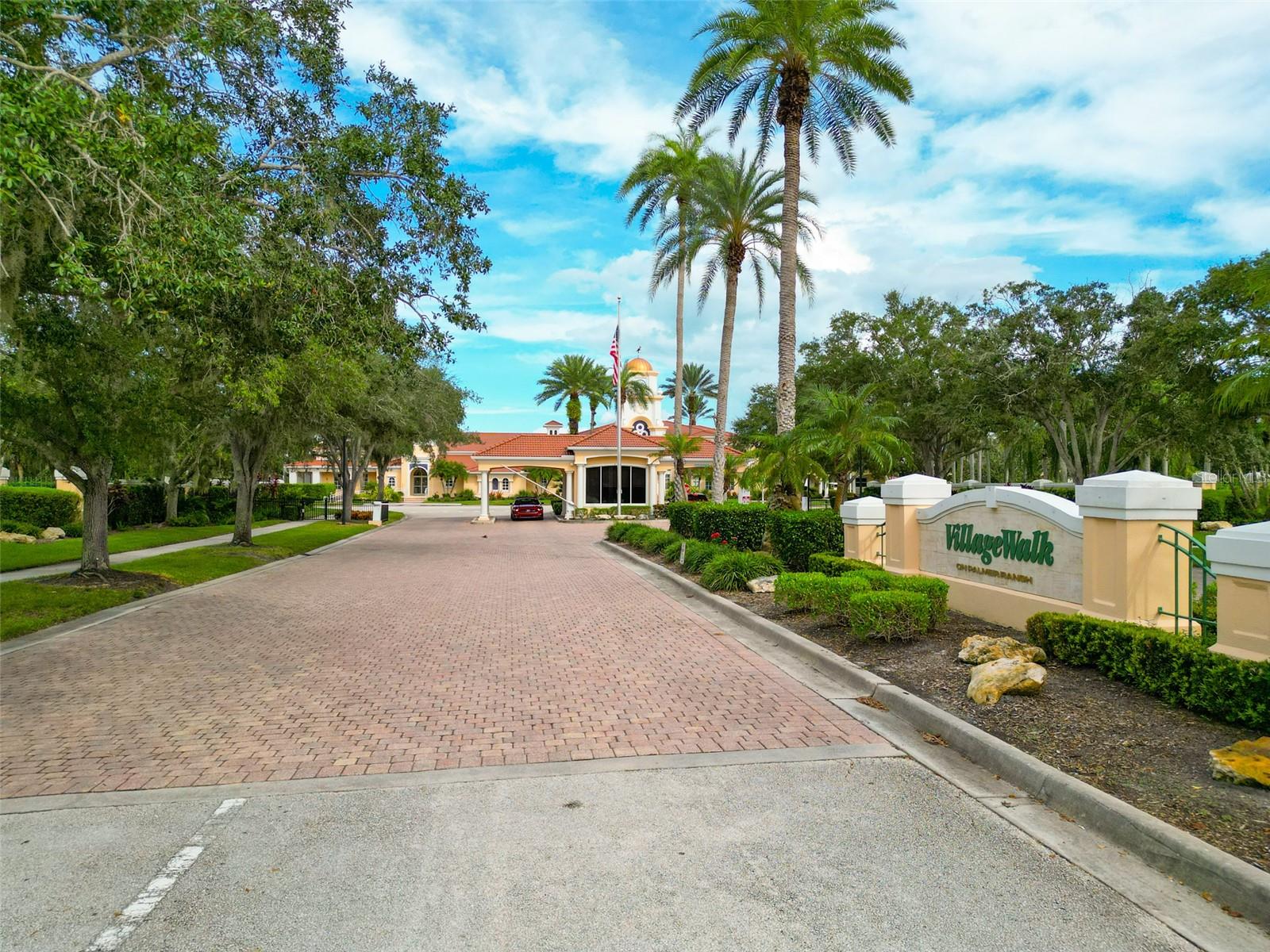 VillageWalk community entrance with a brick-paved drive, palm trees, and a landscaped sign.