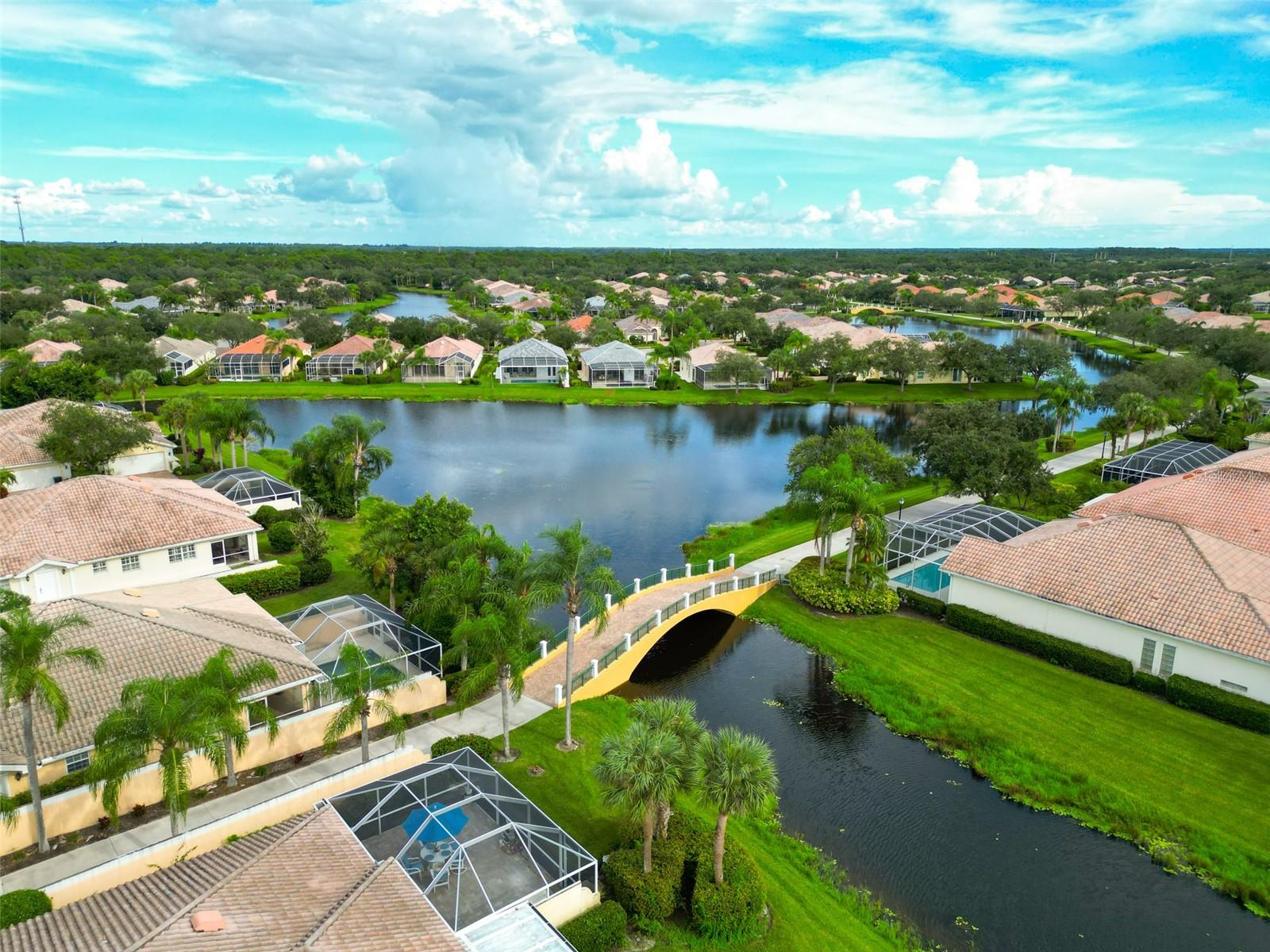 Aerial view of homes around a lake, with a canal and bridge in the foreground.