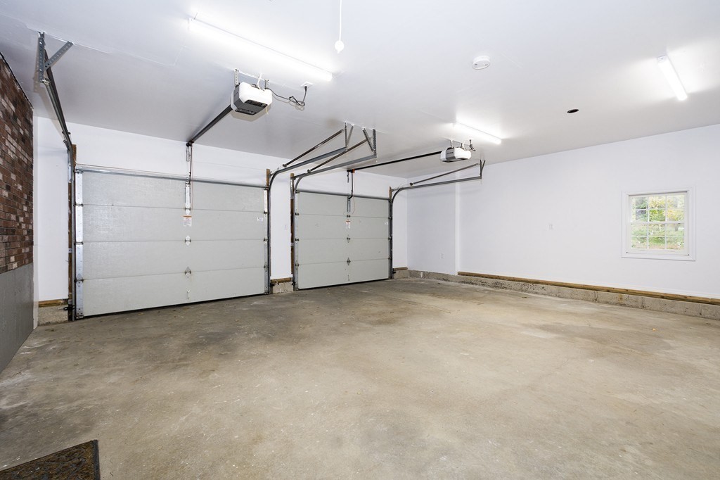 Two-car garage with overhead doors, concrete floor, and a small window.