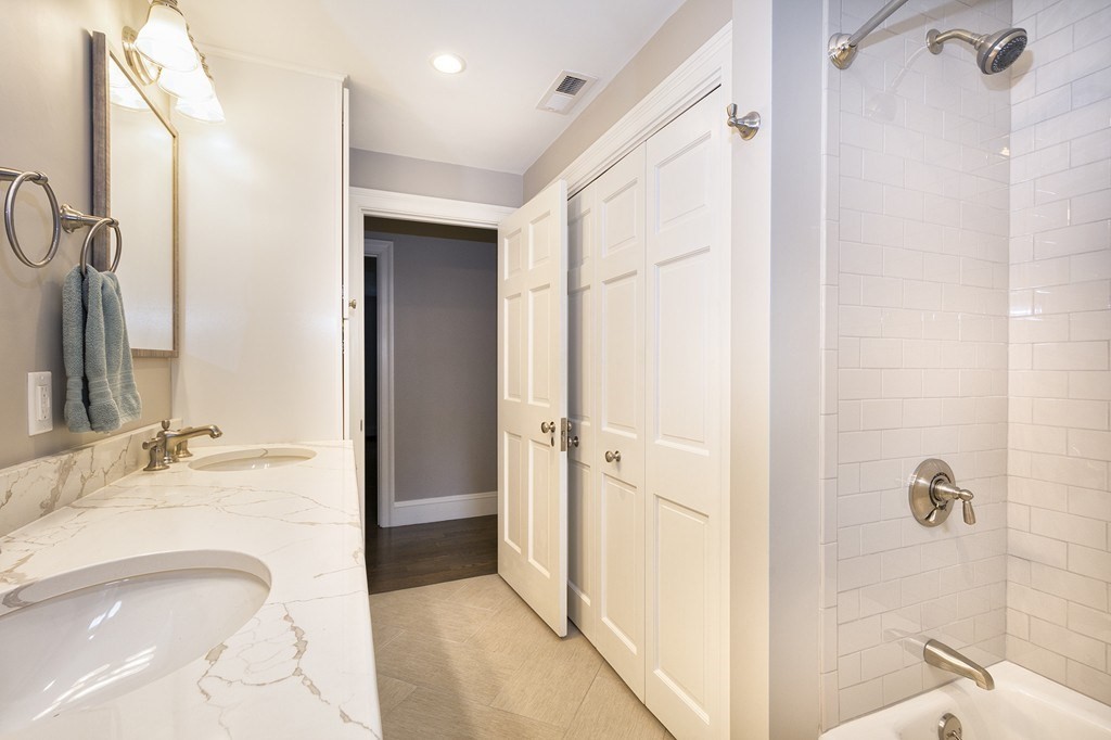 Bathroom with a double-sink vanity and a white subway-tile shower.