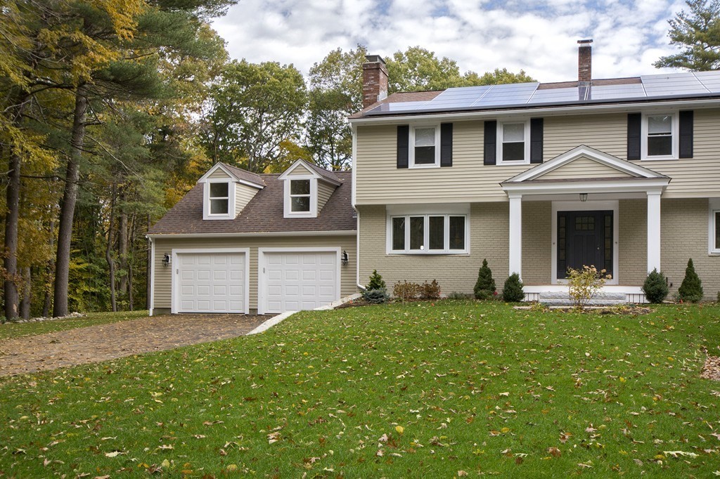 Beige two-story house with solar panels, a covered entry, and an attached two-car garage.