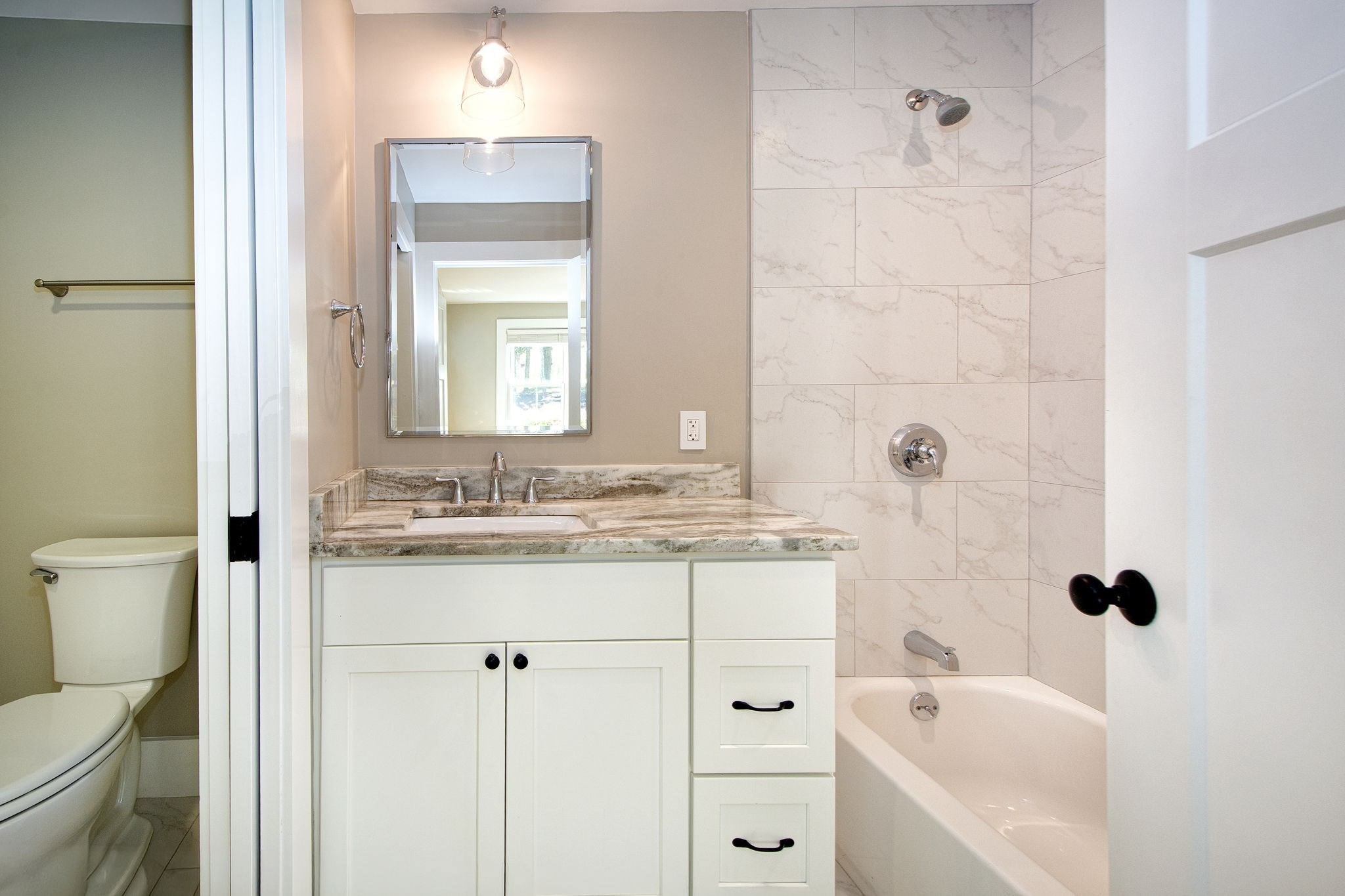 Bathroom with a marble-look vanity and tiled tub and shower.
