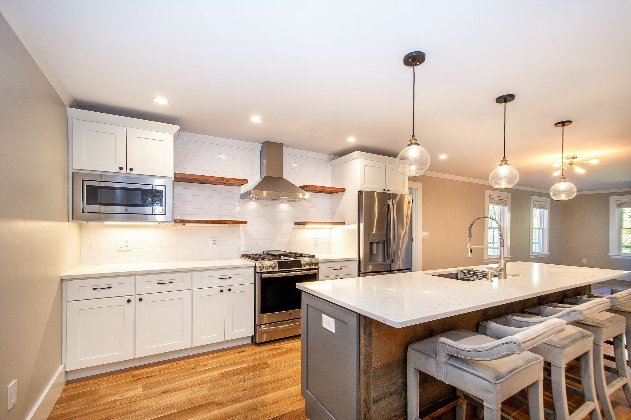 Open kitchen with white cabinets, stainless steel appliances, and a large island with bar seating.